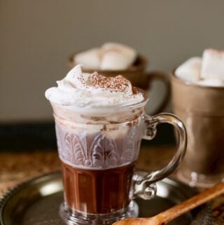 hot chocolate on a table with two other cups with marshmallows