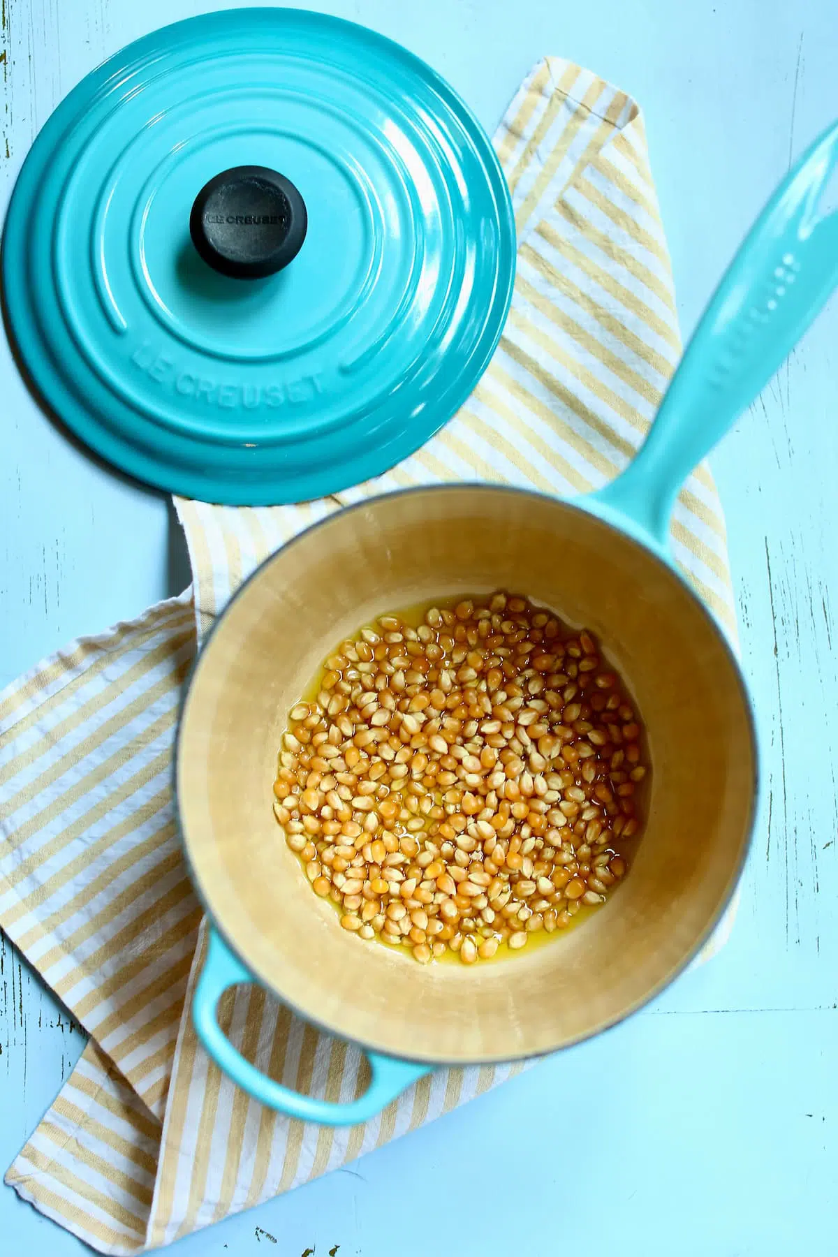 a blue saucepan of uncooked popcorn kernels.