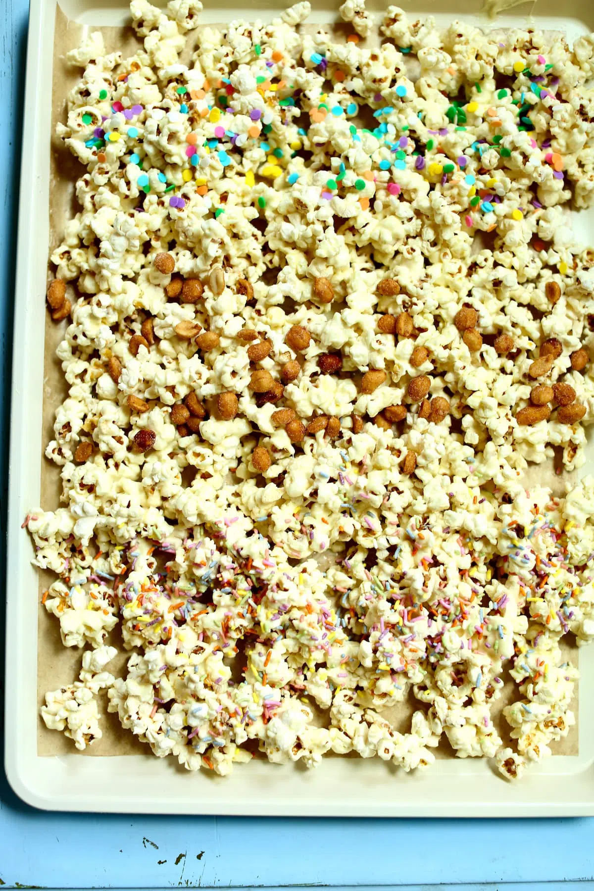 a baking sheet of popcorn with white chocolate and peanuts and sprinkles. 