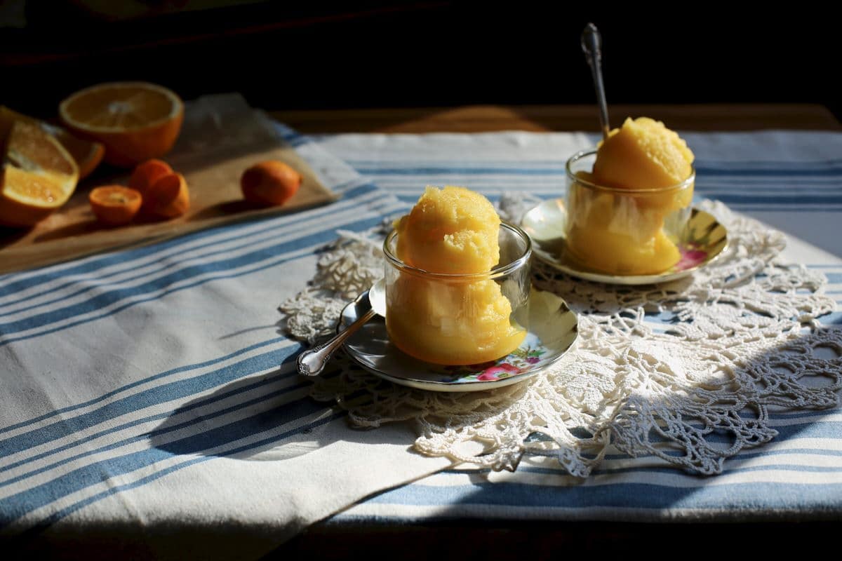 two cups of sorbet on a table with lace and oranges