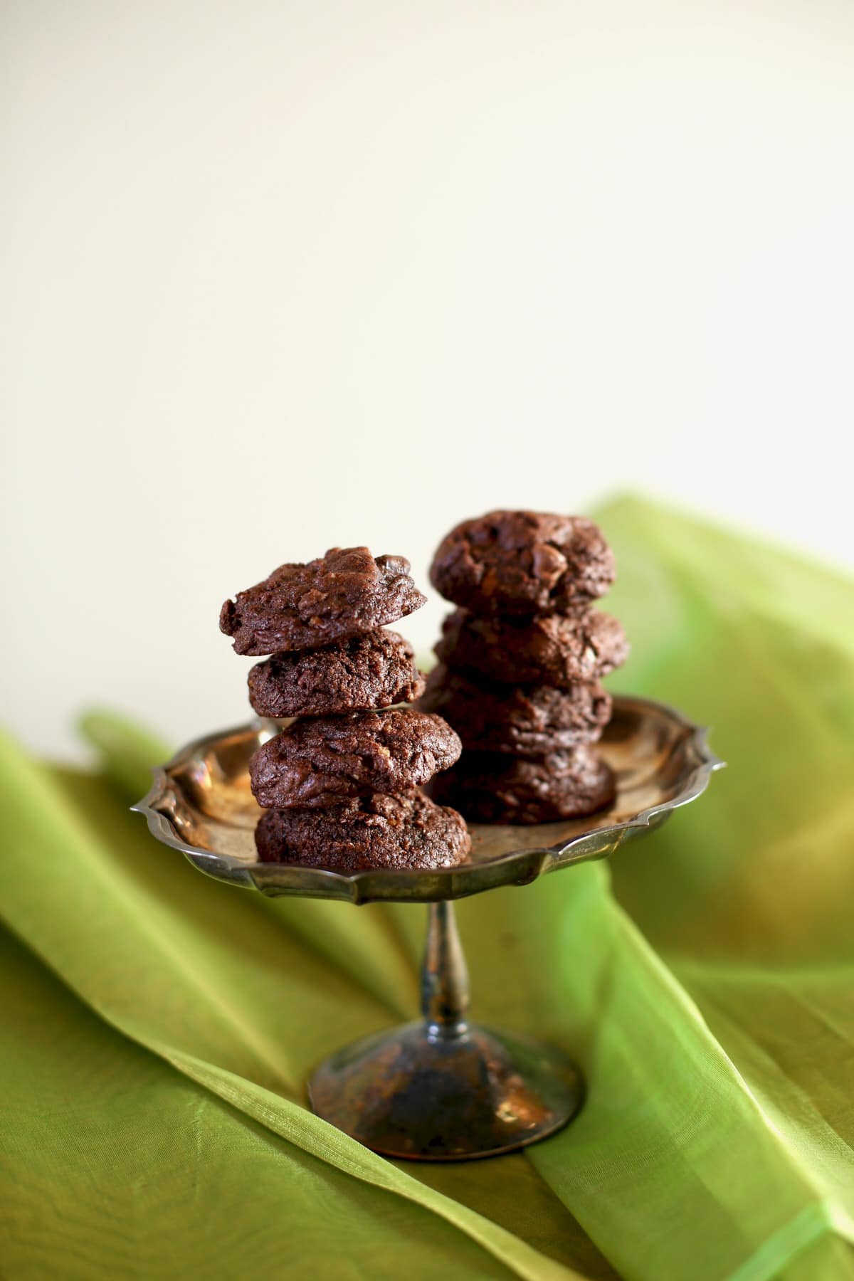 chocolate cookies on a silver tray with green background