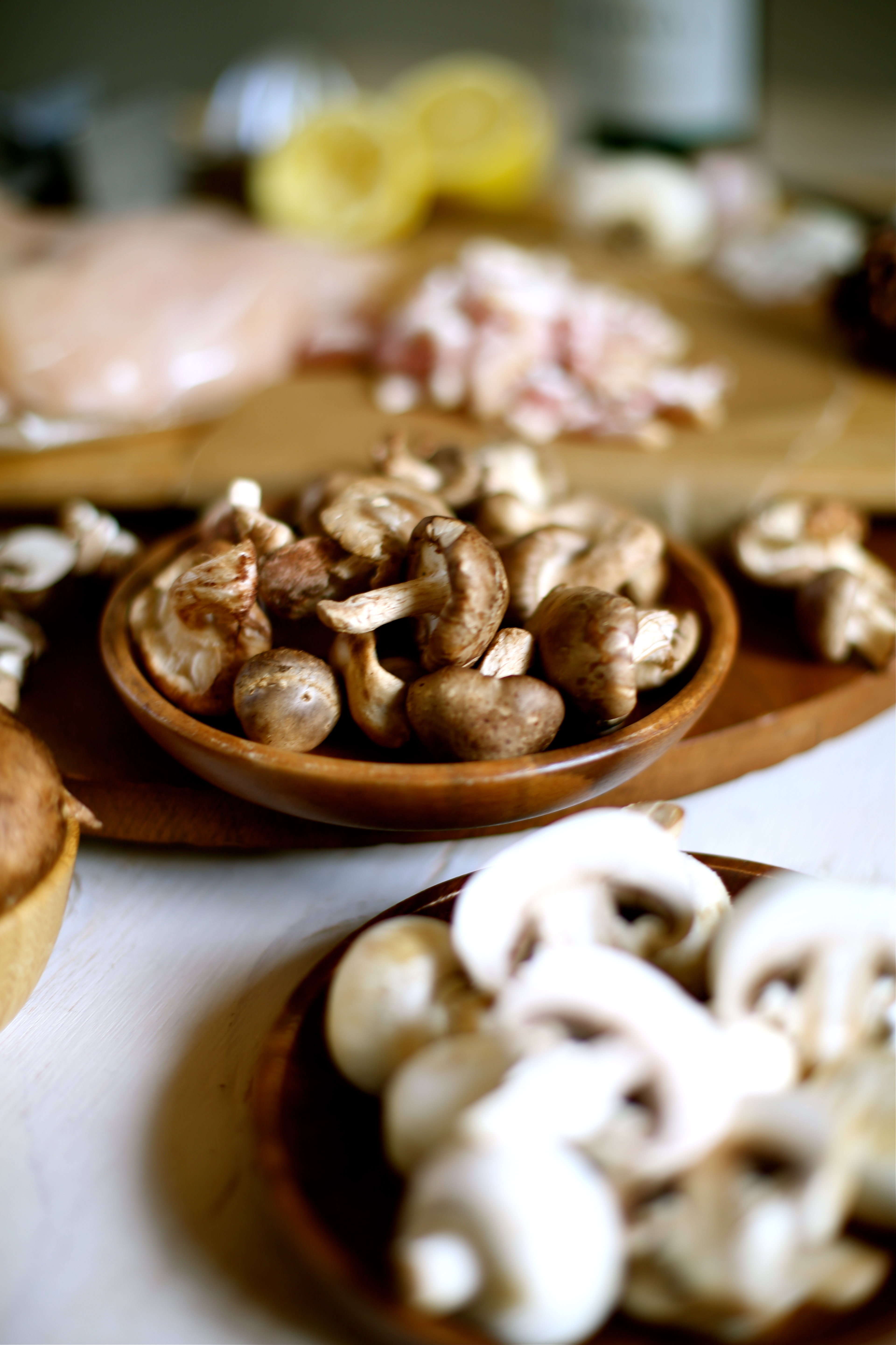 a table with raw chicken breasts and mushrooms in bowls ready to be prepped 