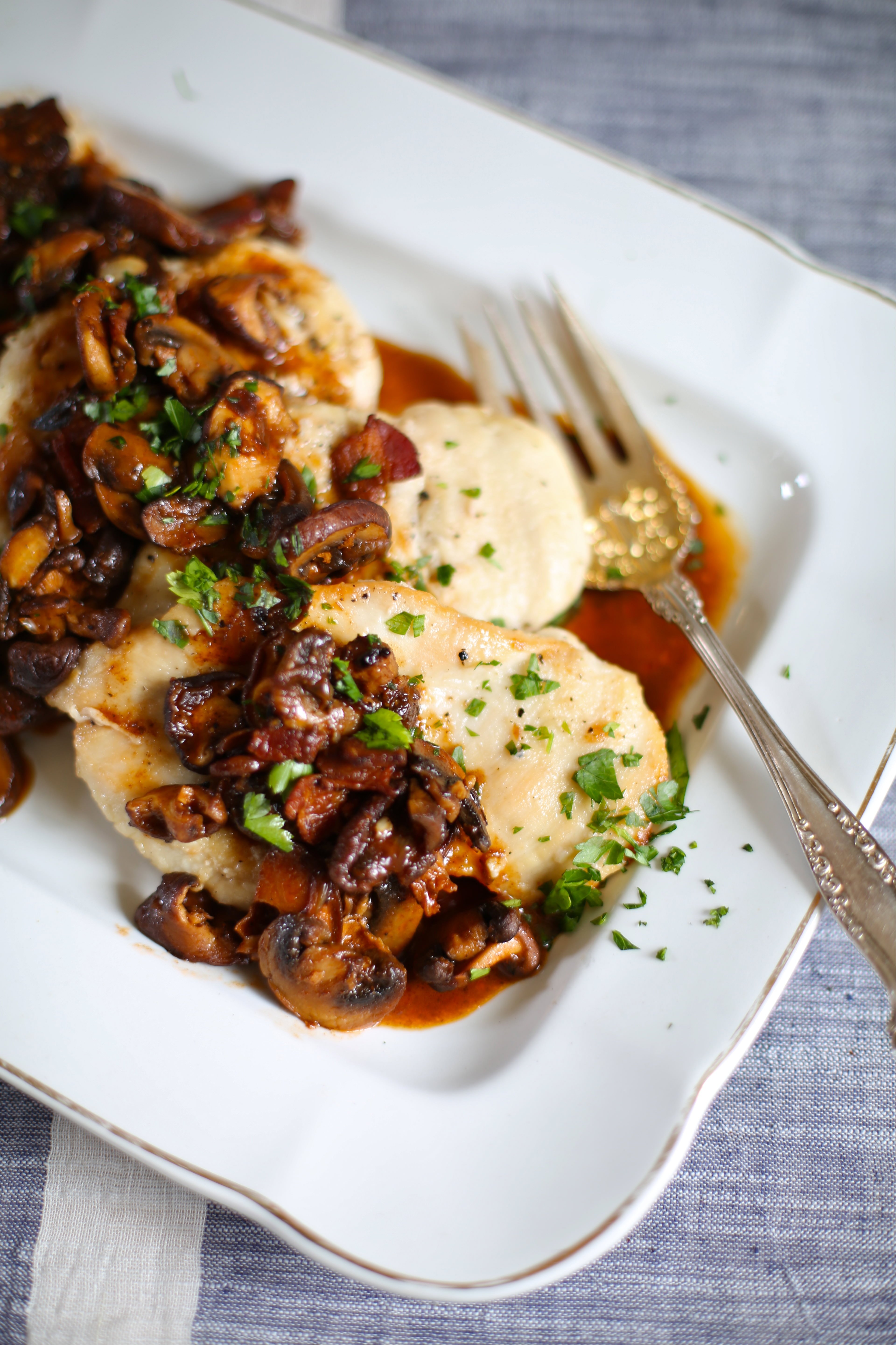 chicken marsala pieces on a white platter with a serving fork. 