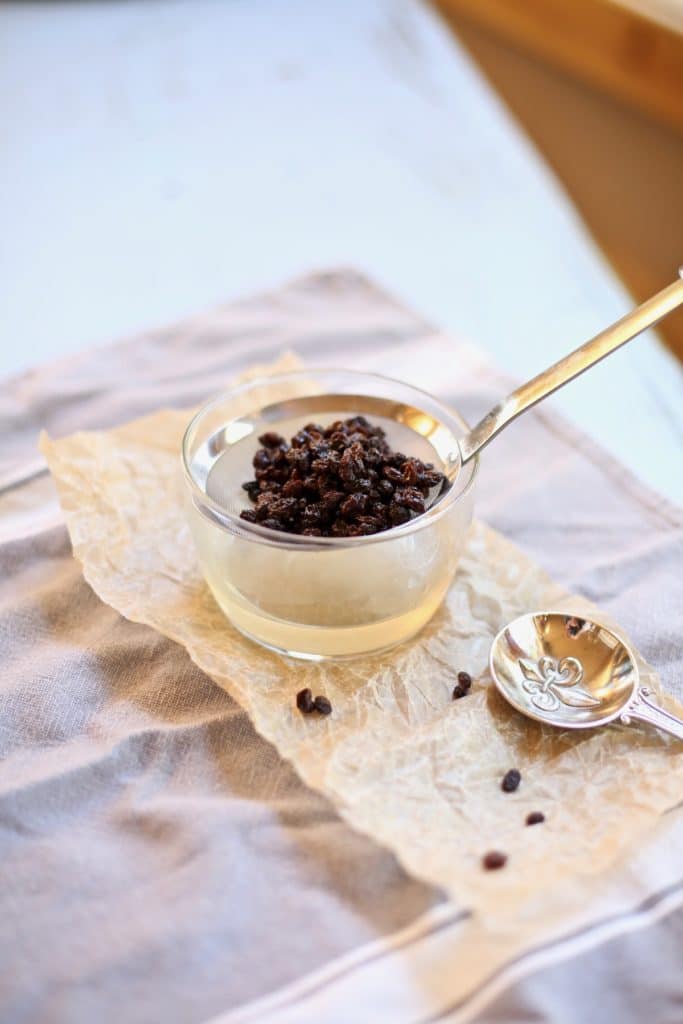 currants in a stainer with a tablespoon