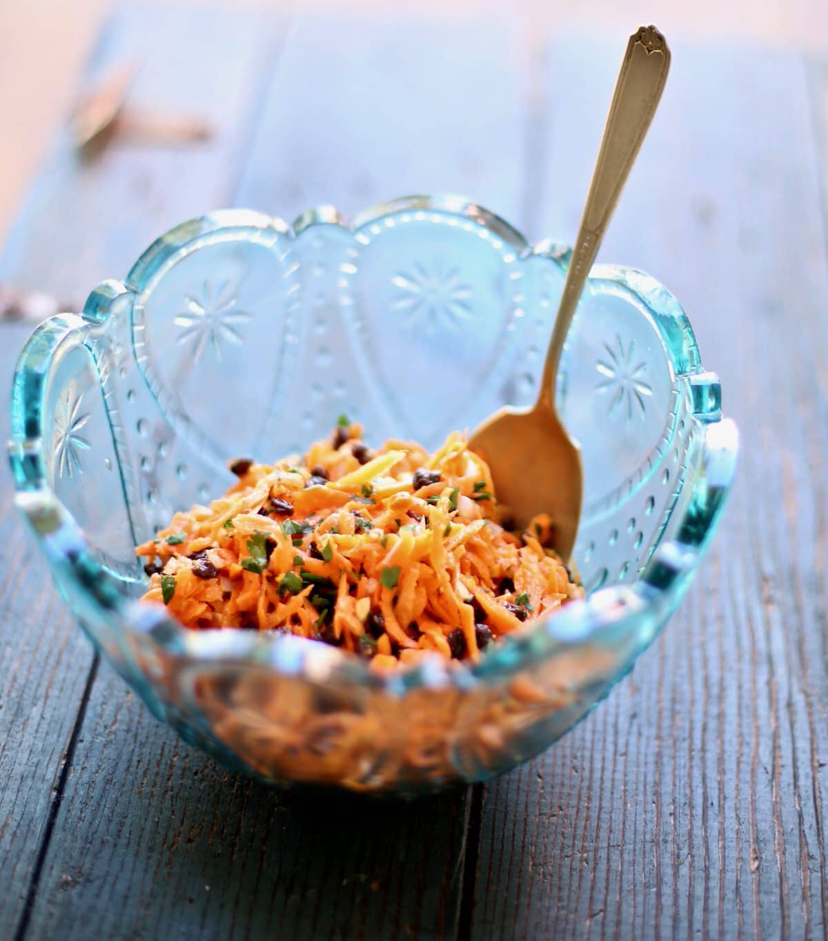 carrot salad in a blue bowl in a wood table