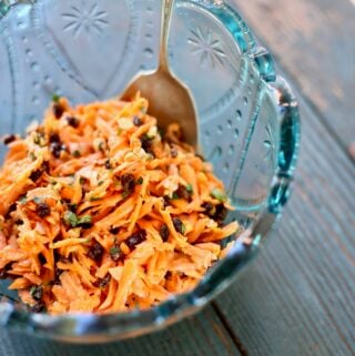 carrot salad in a blue bowl with a spoon