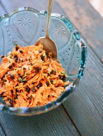 carrot salad in a blue bowl with a spoon