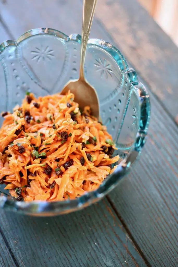 carrot salad in a blue bowl with a spoon