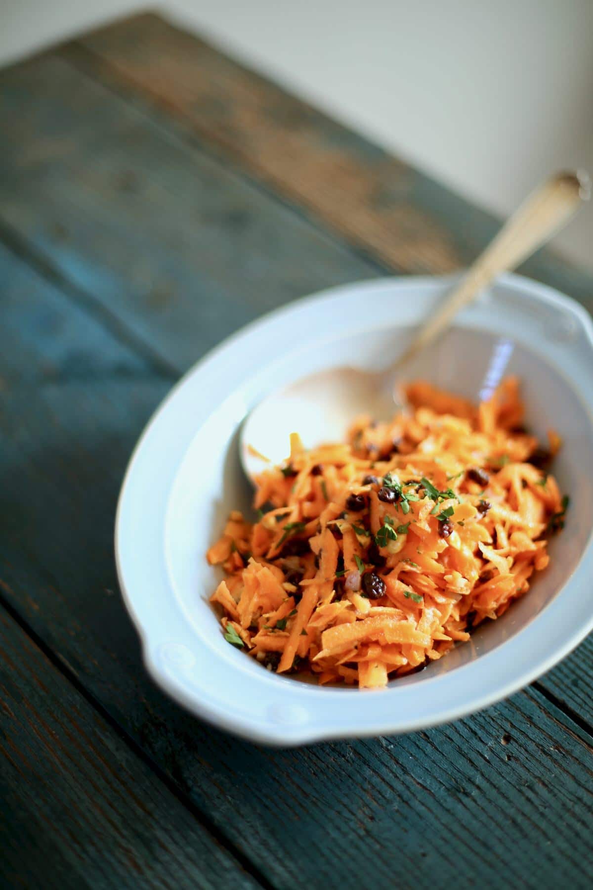 carrot salad in a blue bowl with a spoon