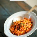 Carrot salad on a table in a blue bowl with text