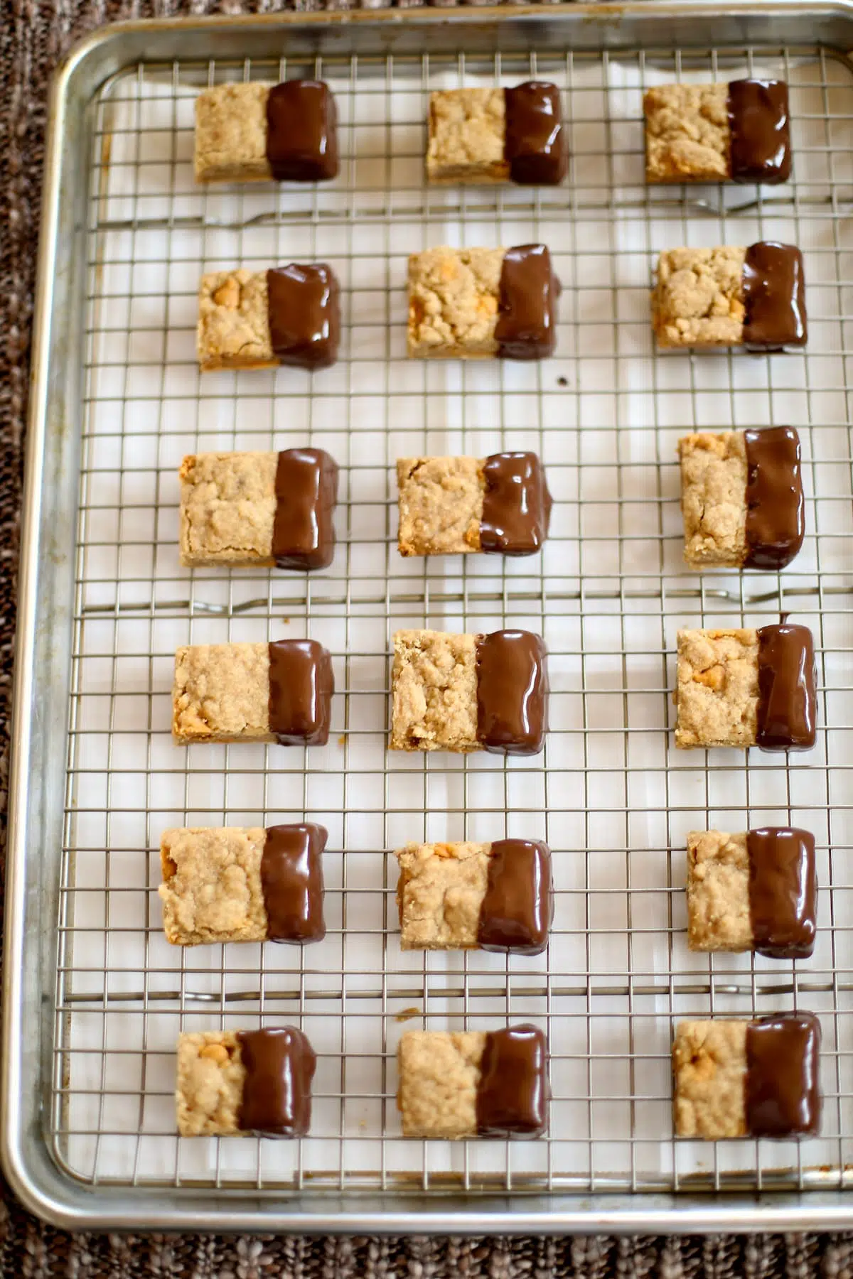 a rack of shortbread dipped in chocolate on a baking sheet.