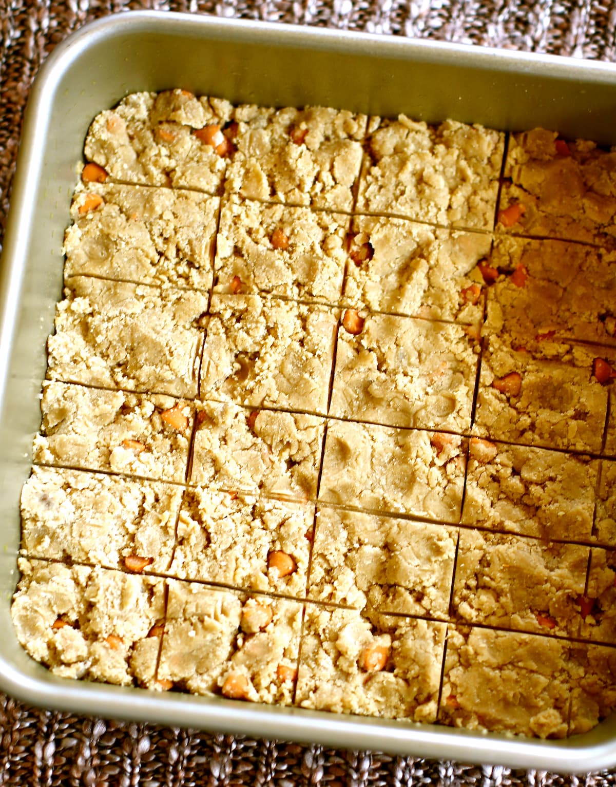 butterscotch shortbread in a square pan, cut/scored and ready for the oven.