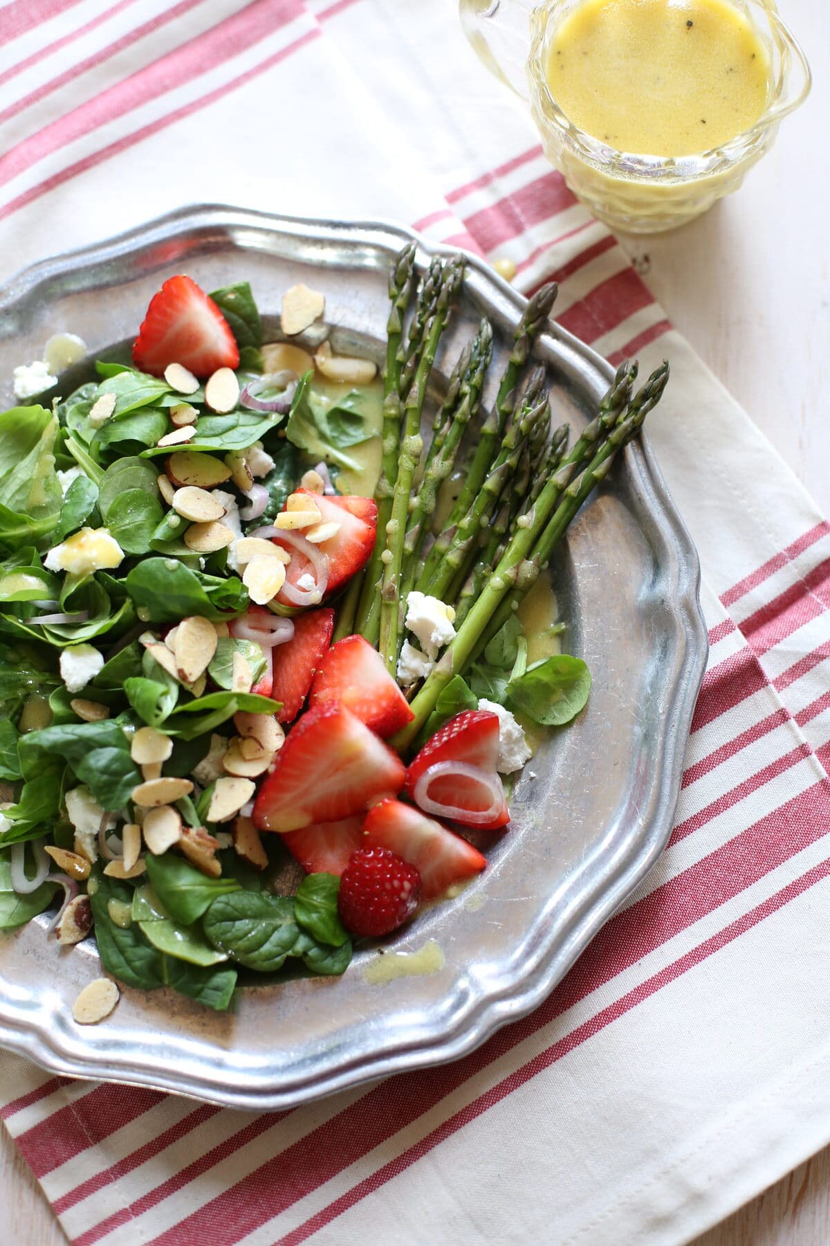 salad with strawberries on a silver plate on a tablecloth with stripes