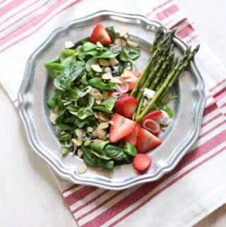 green salad and dressing on a silver plate with striped tablecloth