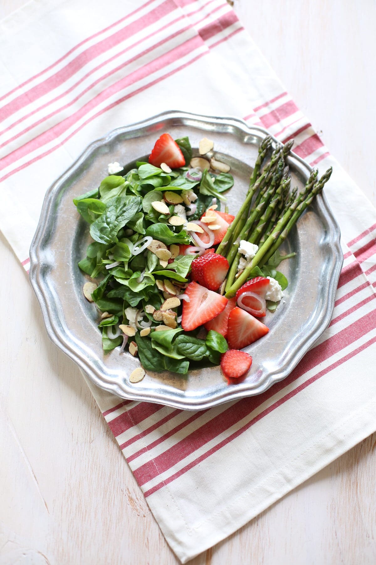 green salad and dressing on a silver plate with striped tablecloth