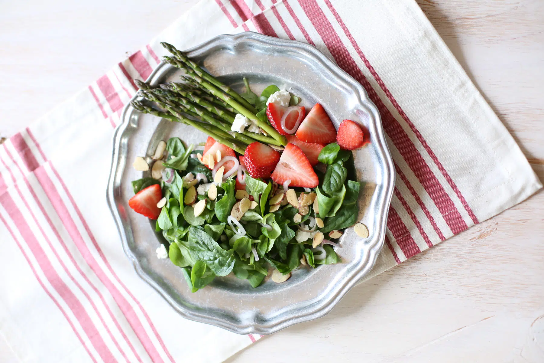 green salad and dressing on a silver plate with striped tablecloth