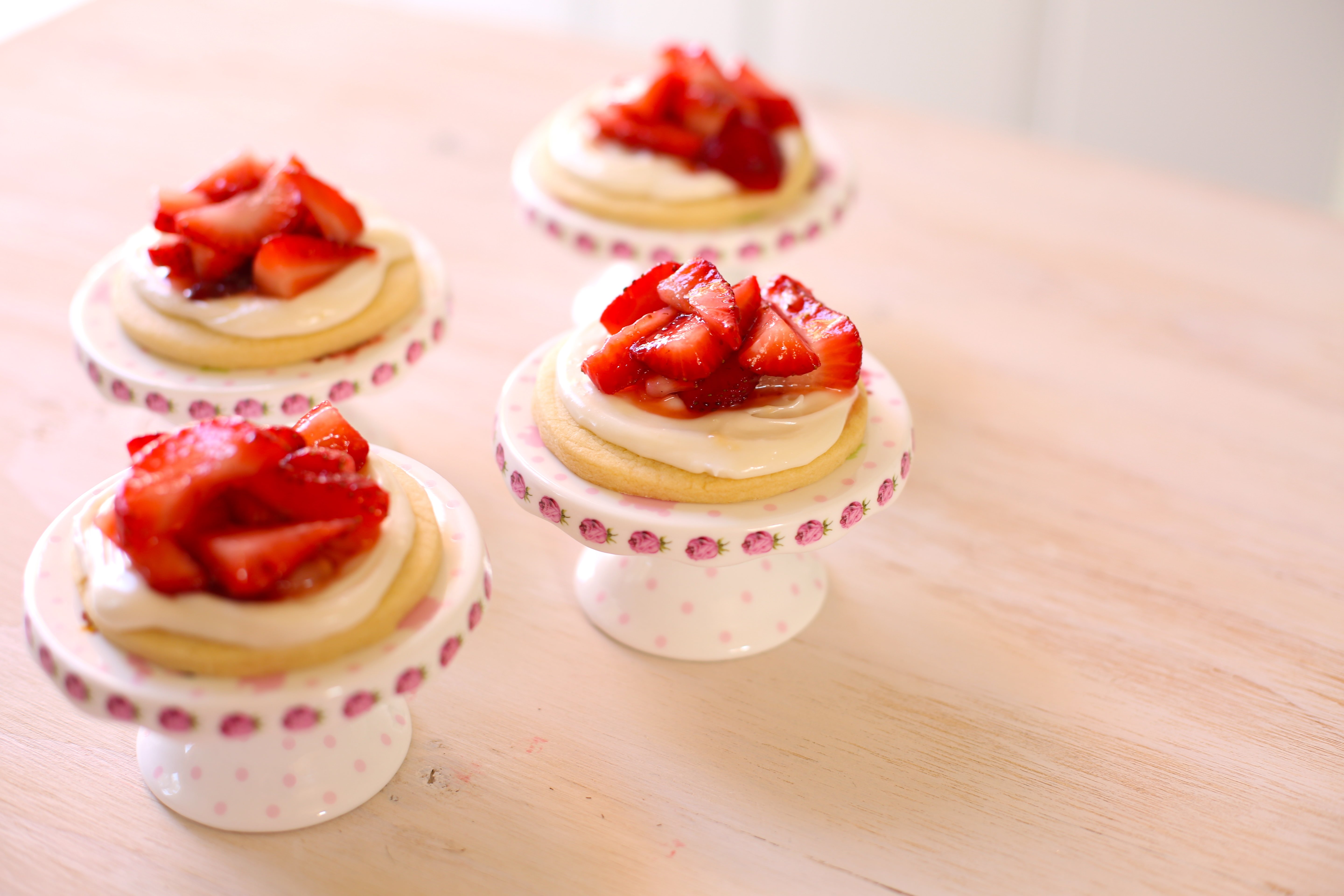 Four Strawberry Shortcake Cookies on footer stands on a table 