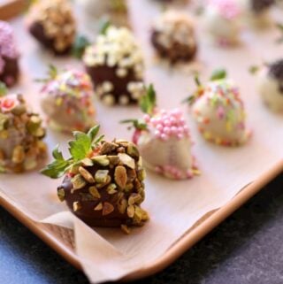 a tray of strawberries on a baking sheet with multiple kinds of toppings