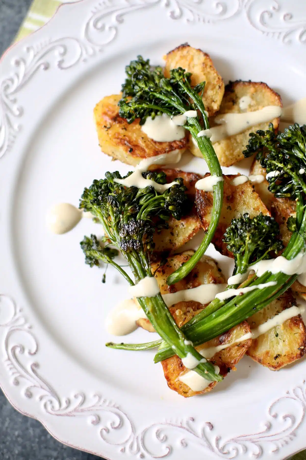 a plate of potatoes and broccolini on a white platter.