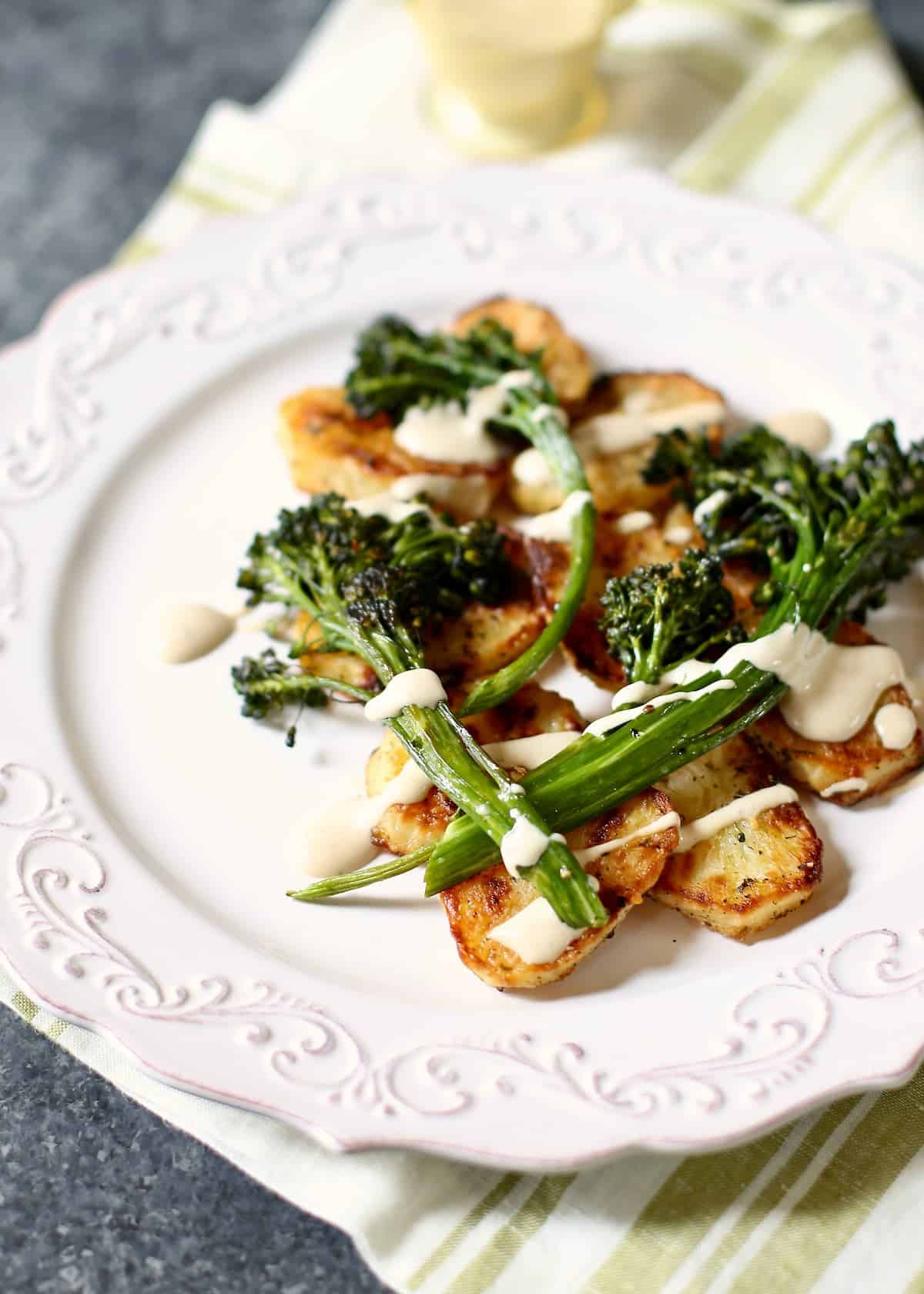 a white plate with broccolini and potatoes on it.
