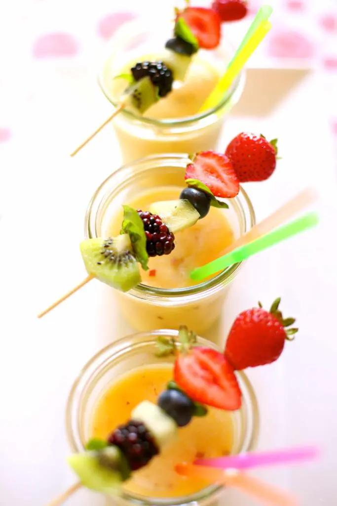 fruit slushes on a white plate with fresh fruit garnish