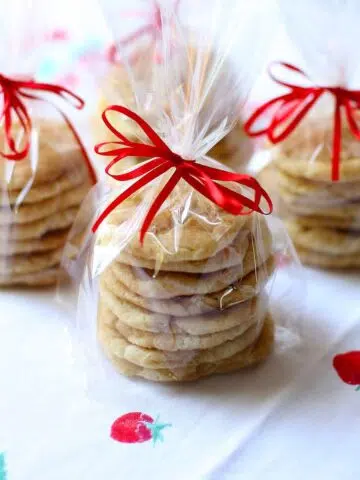 some gift wrapped cookies with red ribbon on a table.