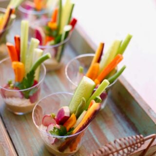 Veggies in plastic cups on a wooden tray