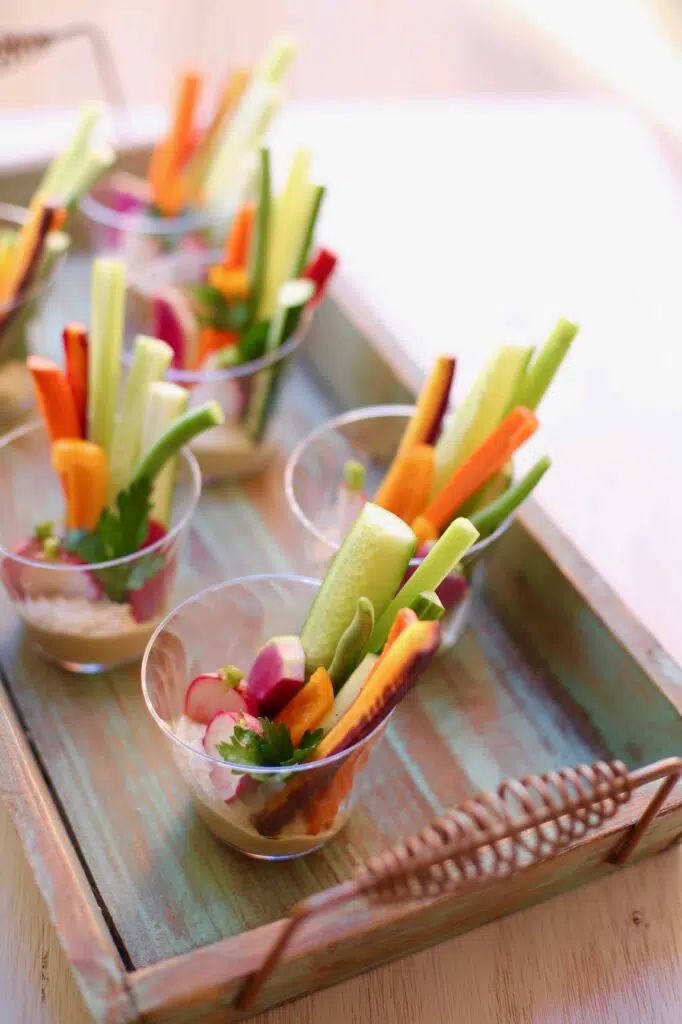 Veggies in plastic cups on a wooden tray
