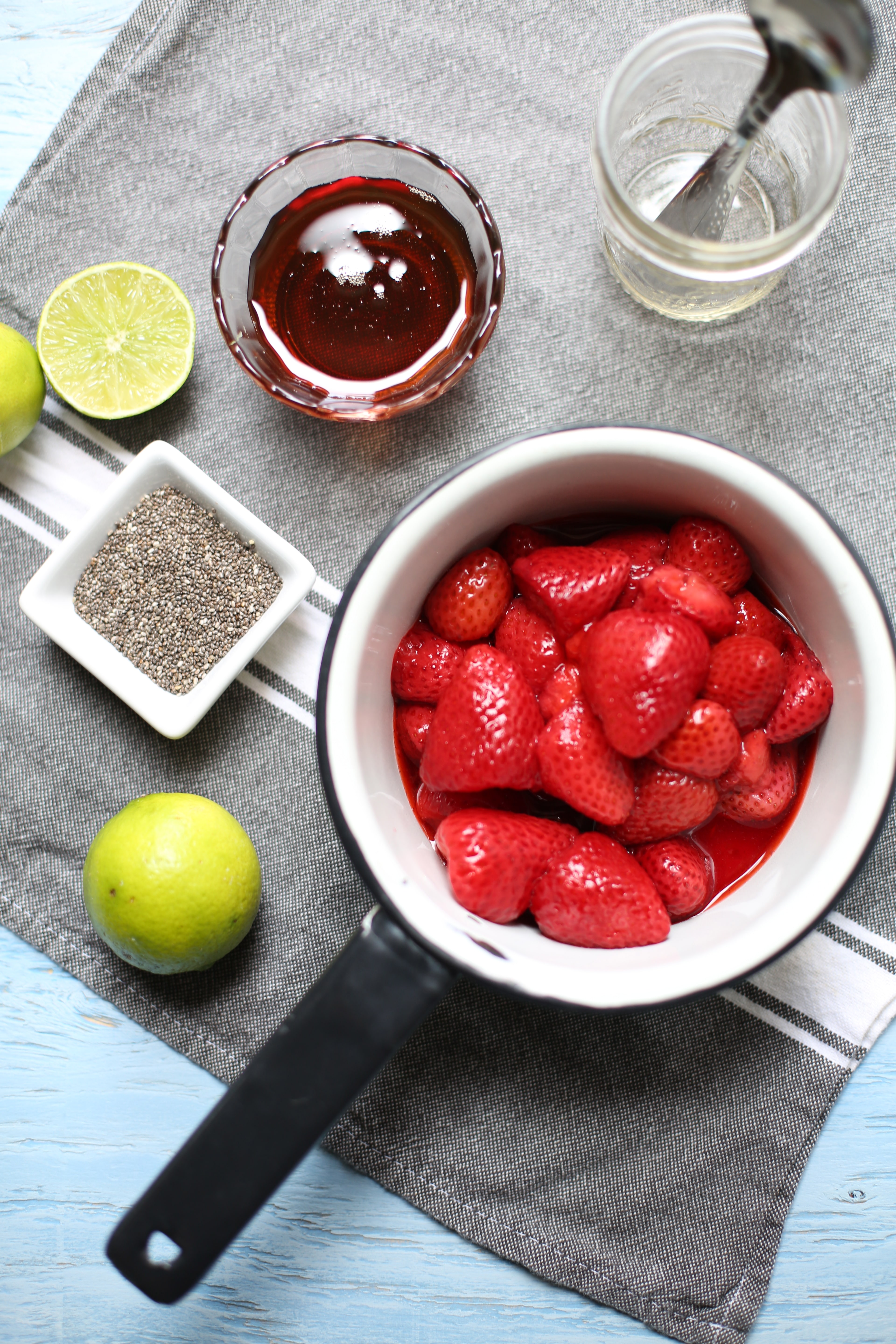 Saucepan of whole strawberries and fresh lime and chia seeds for Cornmeal Pancakes with Strawberry Jam 