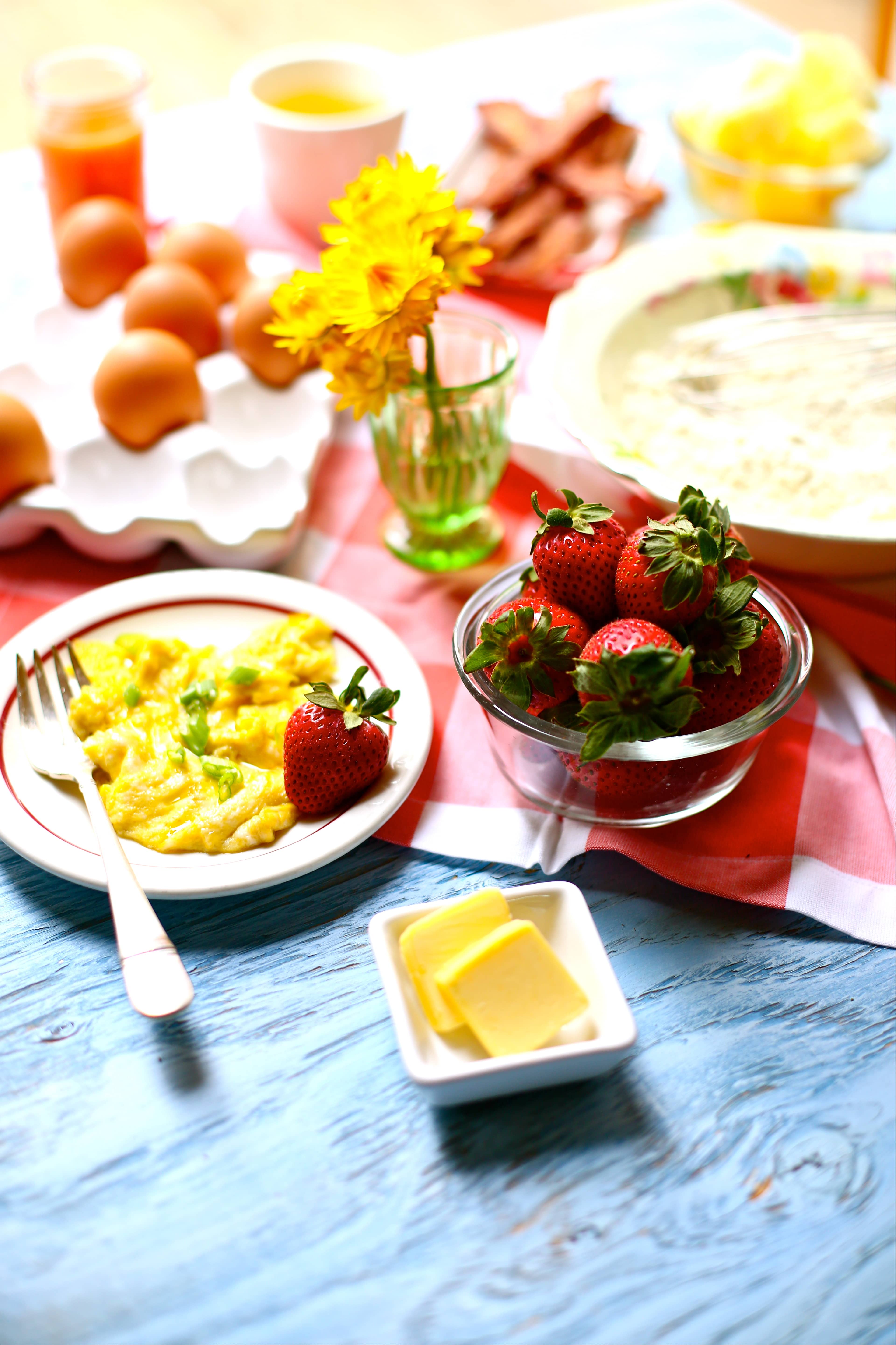 Set up for a Cornmeal Pancakes with Strawberry jam breakfast with scrambled eggs and strawberries 