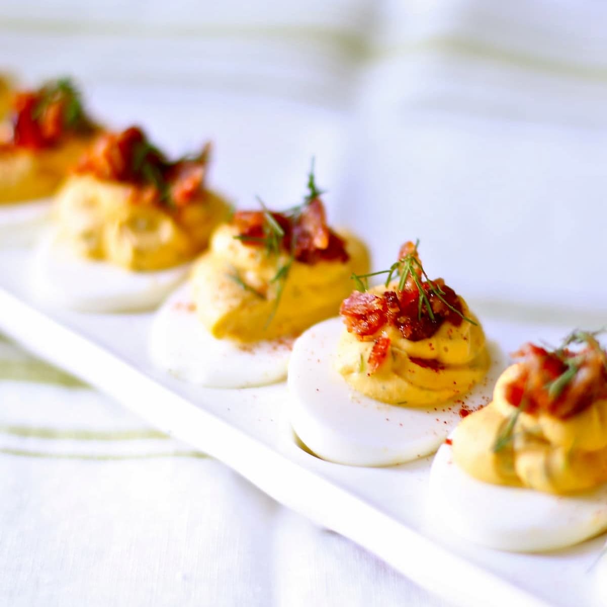 a picture of deviled eggs on a white serving tray.