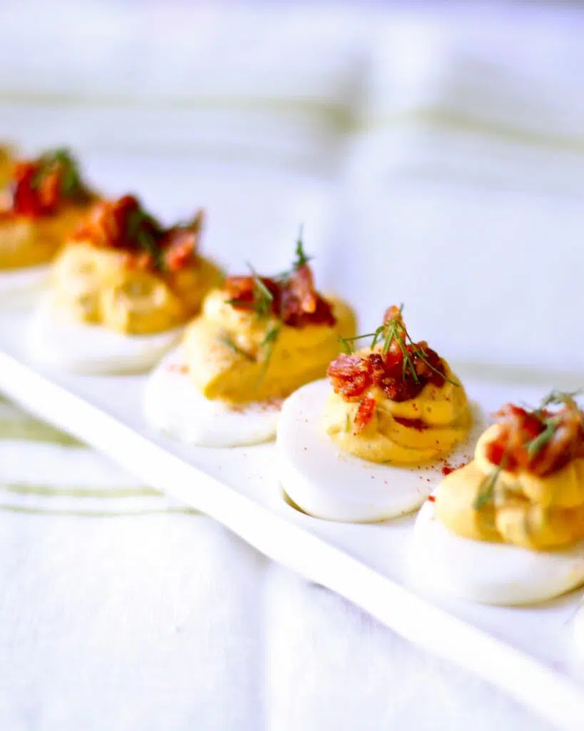 a white tray of deviled eggs, all in a row.