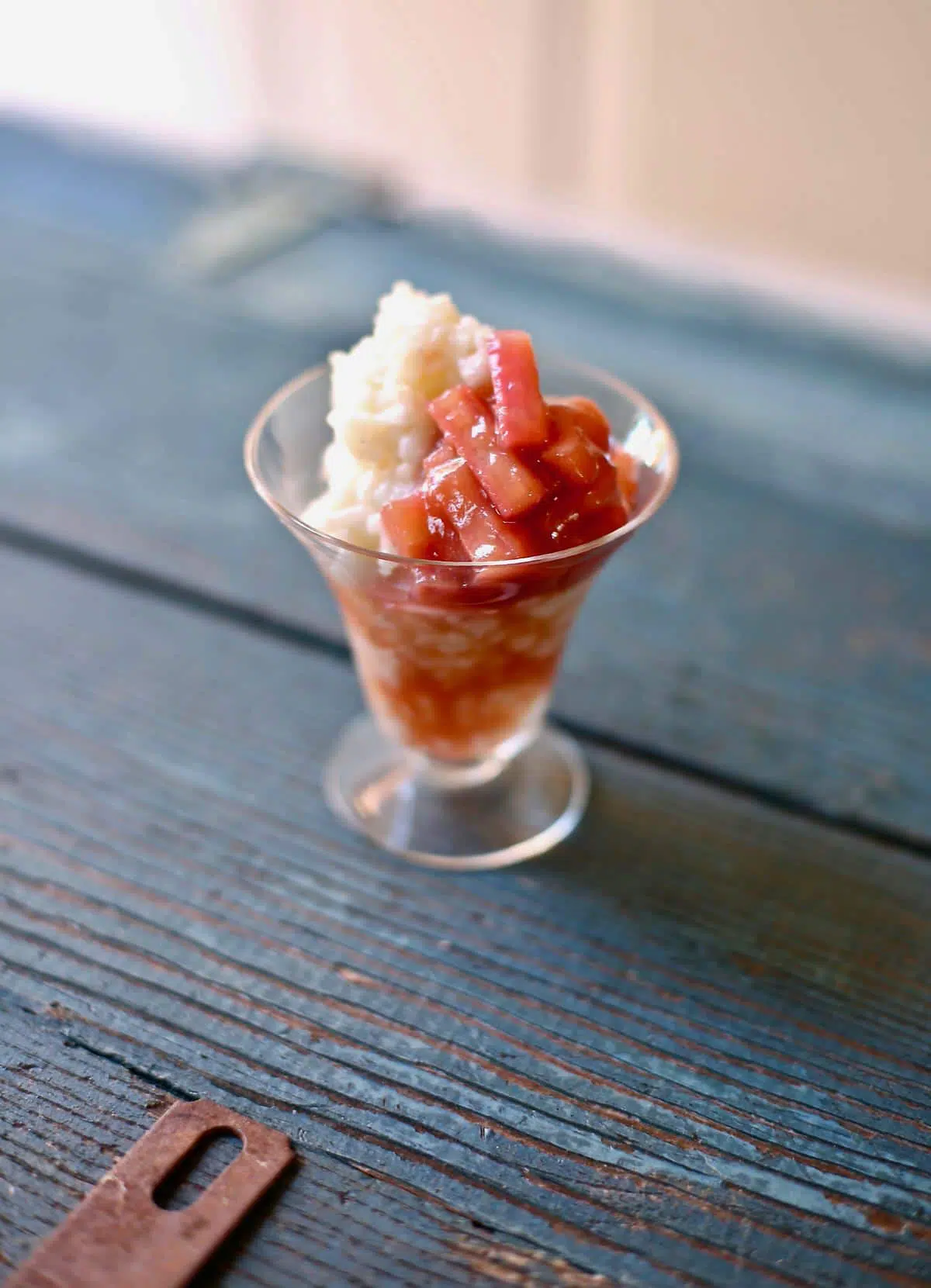 rice pudding with rhubarb in a small glass on a blue table