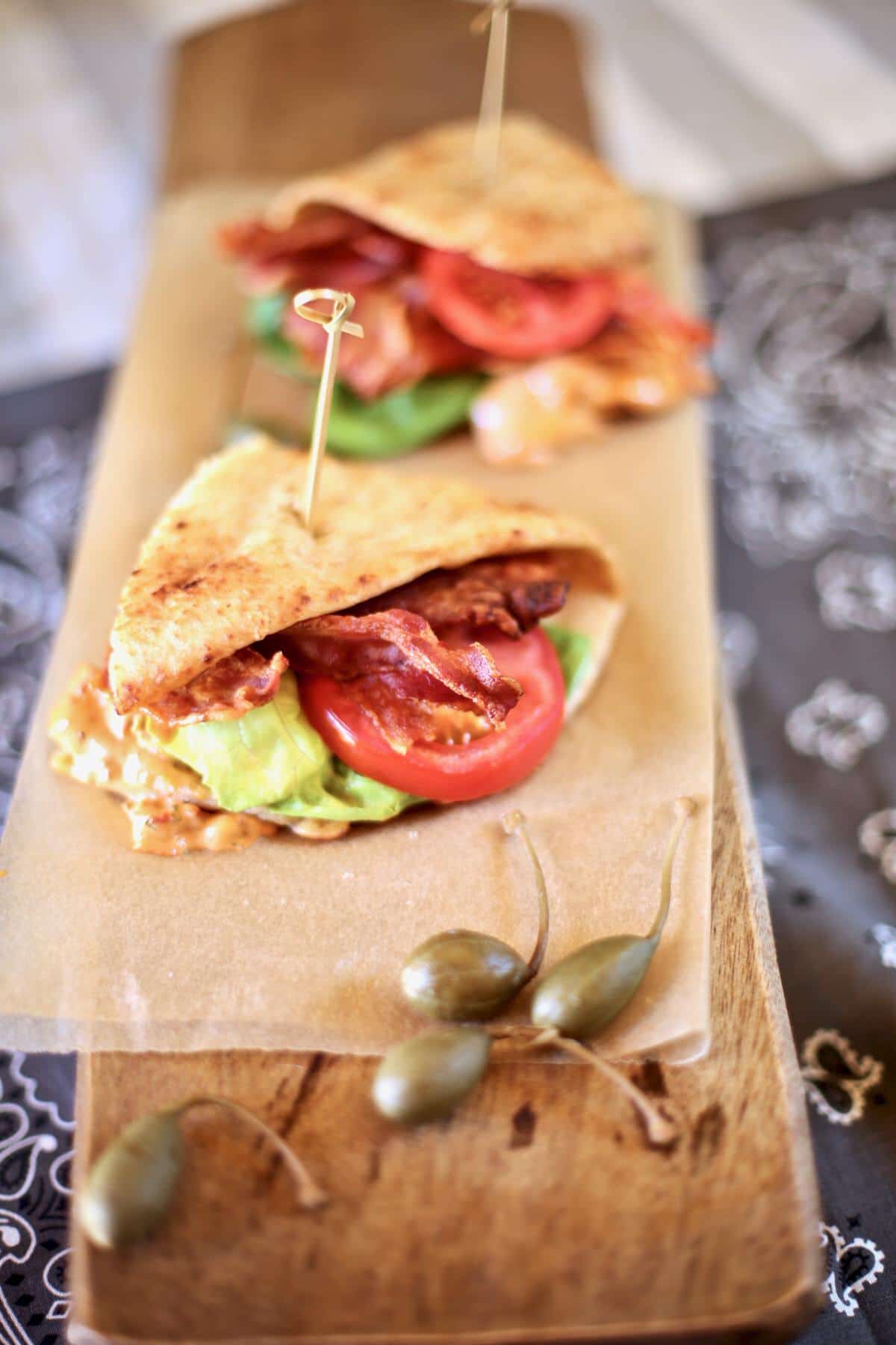 two sandwiches on a board with capers