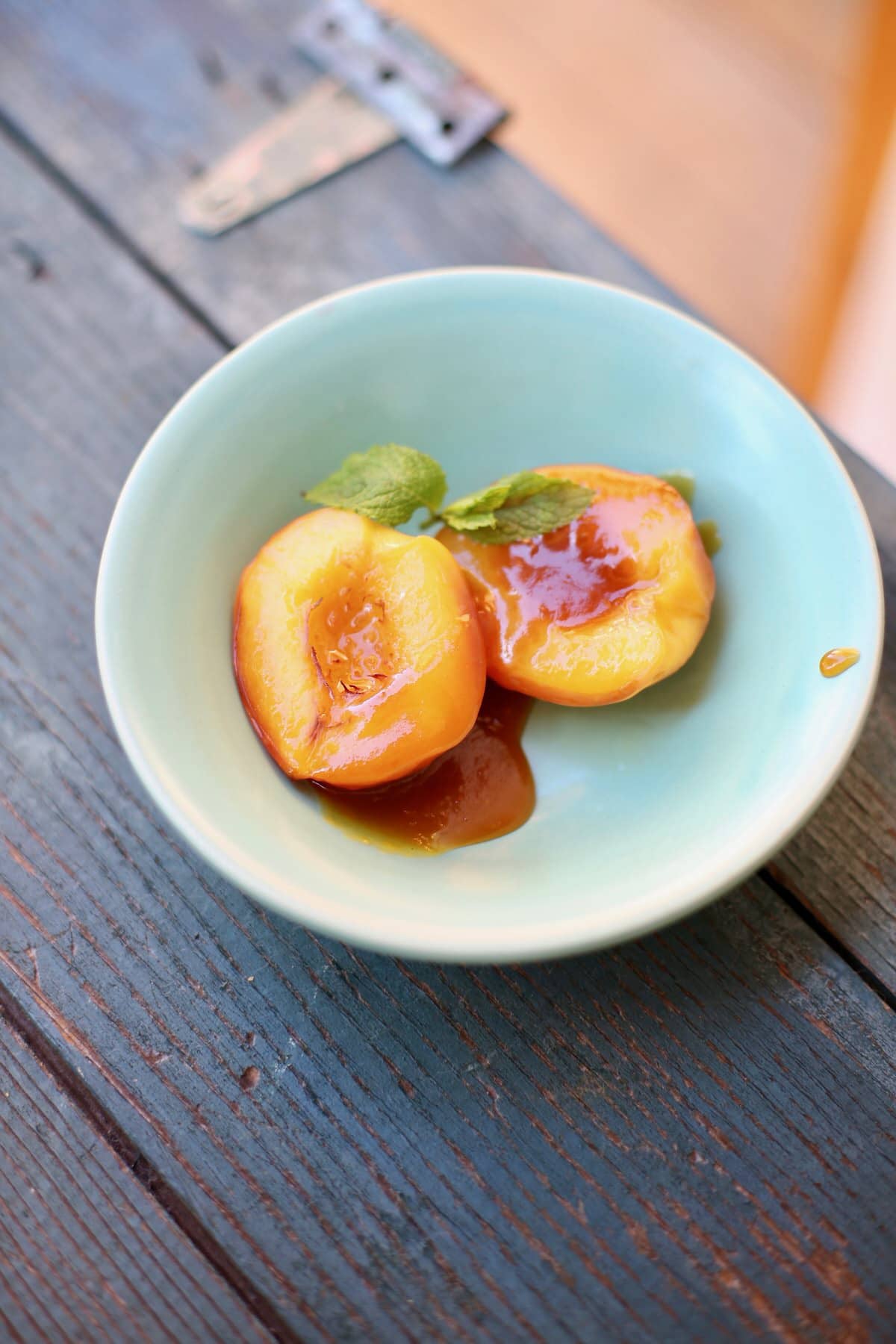 Roasted nectarines in a blue bowl on a blue wooden table