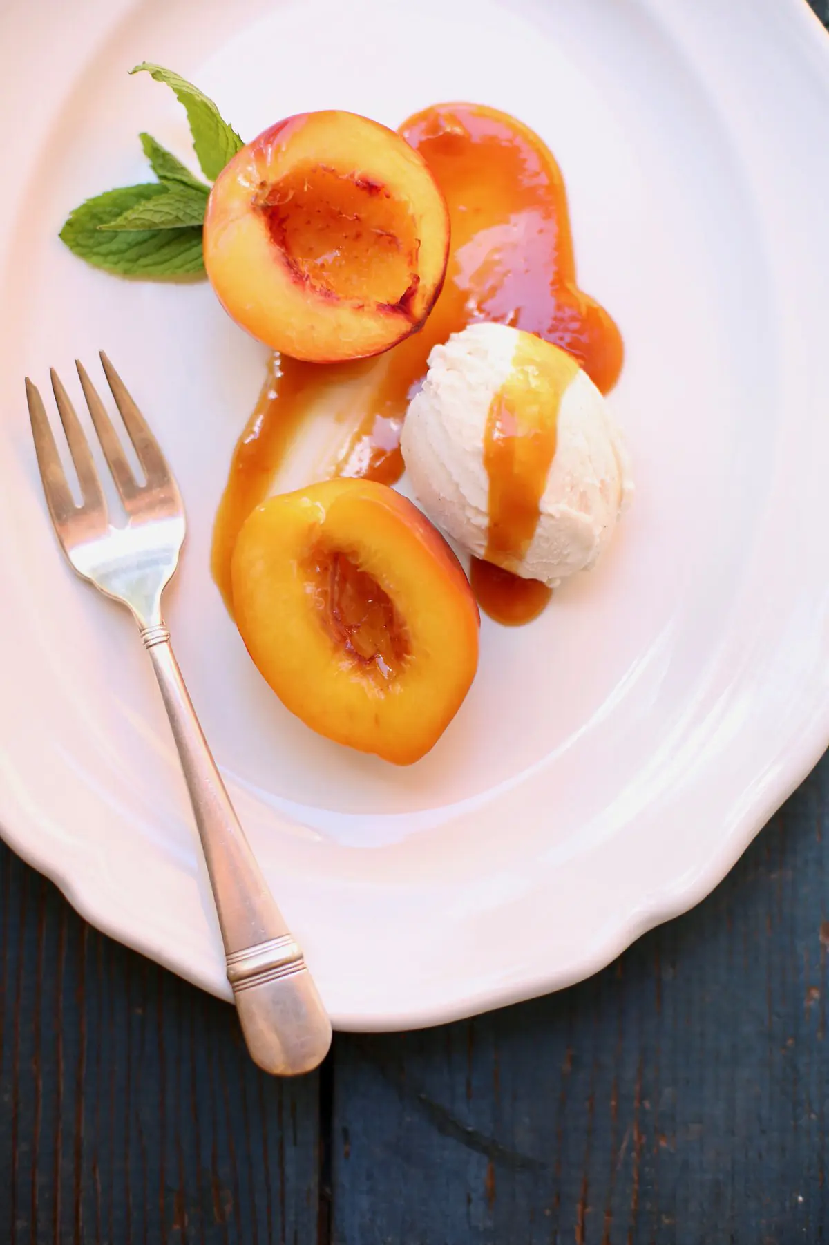 nectarines with caramel sauce on a white plate with silver fork