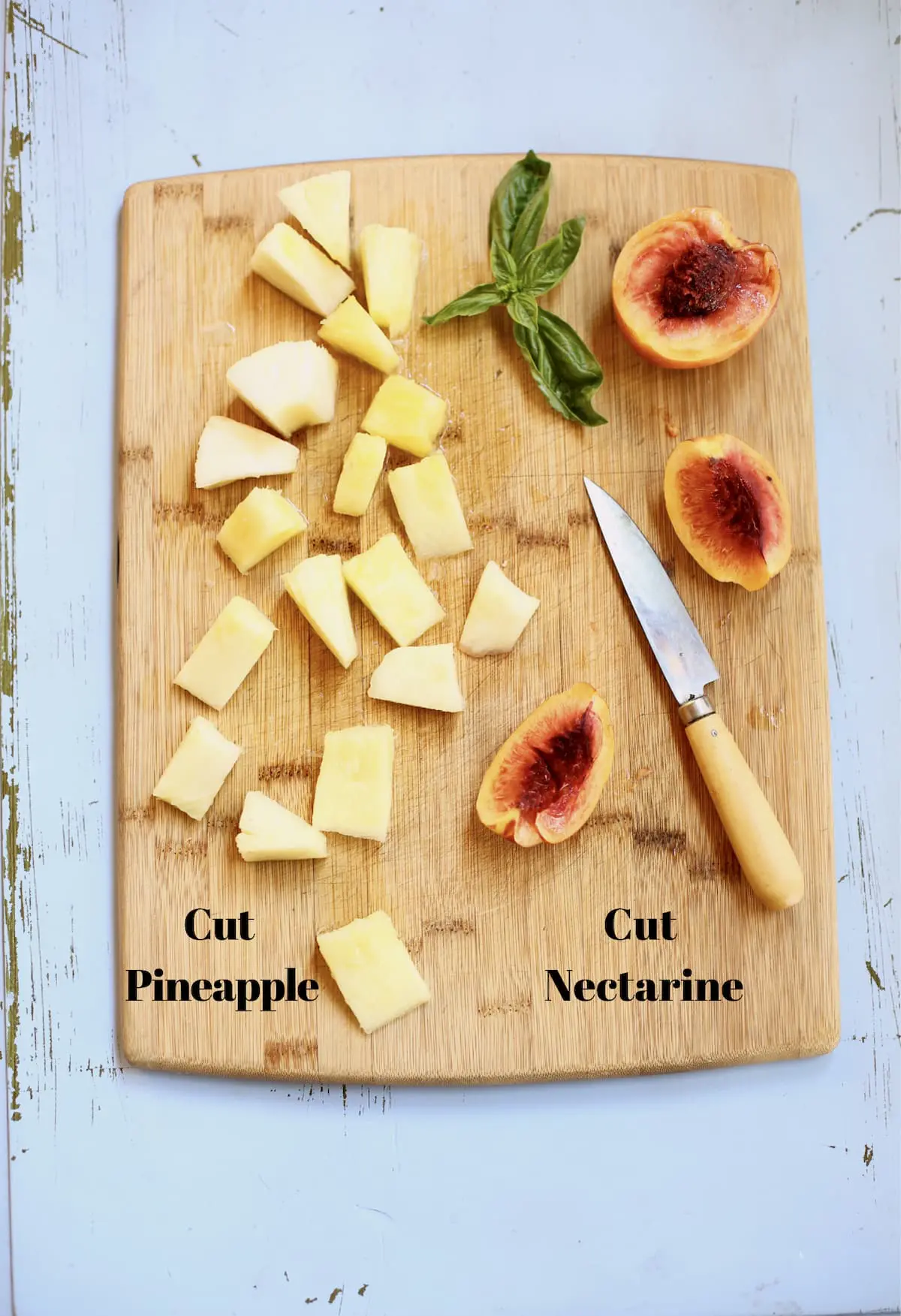 cut pineapple and nectarine and knife on a cutting board