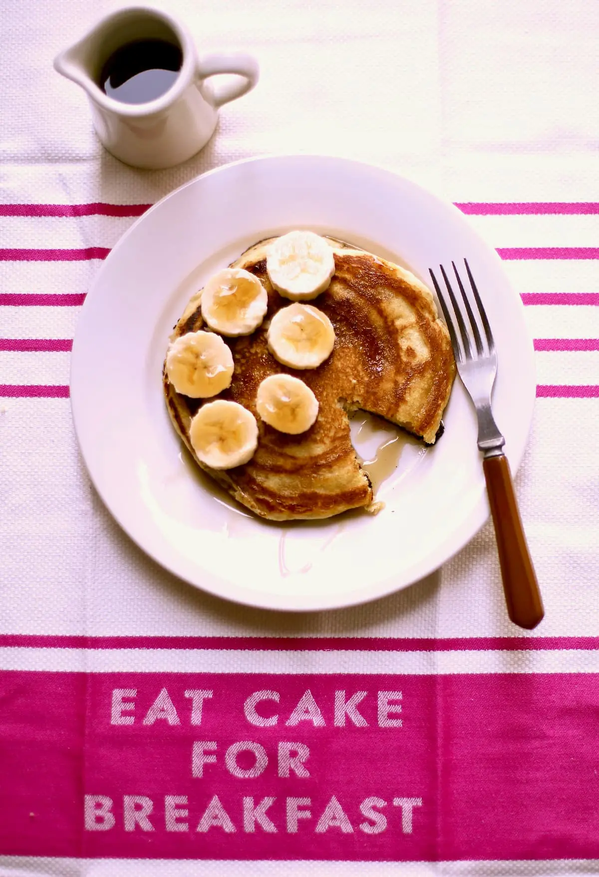 pancakes with bananas on a pink cloth with text