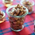 Almonds that are for snacking in a glass jar on a red tablecloth