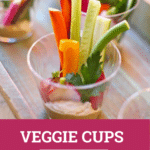 Veggies in a small plastic cup on a wooden tray