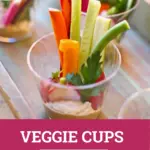 Veggies in a small plastic cup on a wooden tray