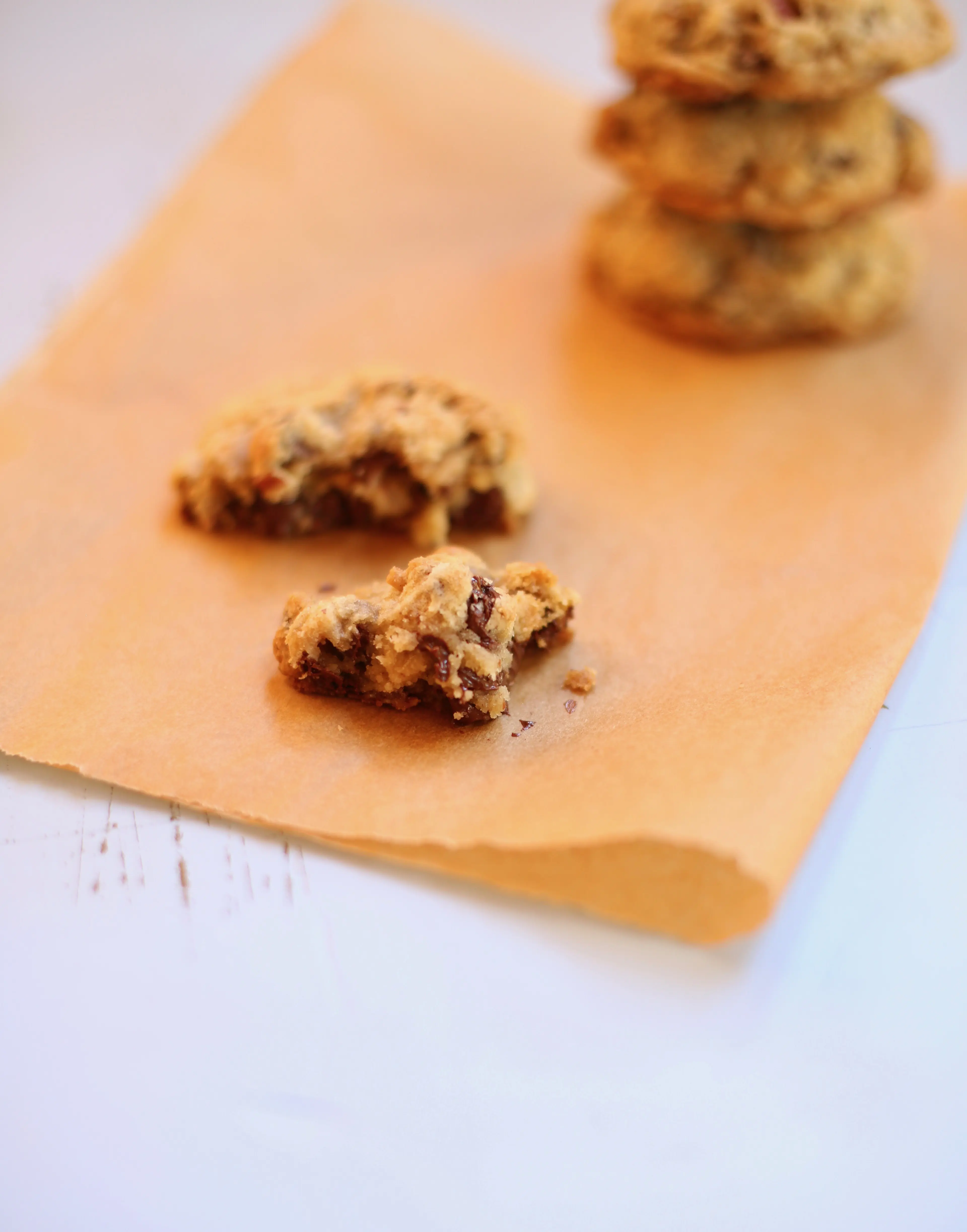 One Favorite Chocolate Chip Cookie broken in half on a piece of natural parchment paper