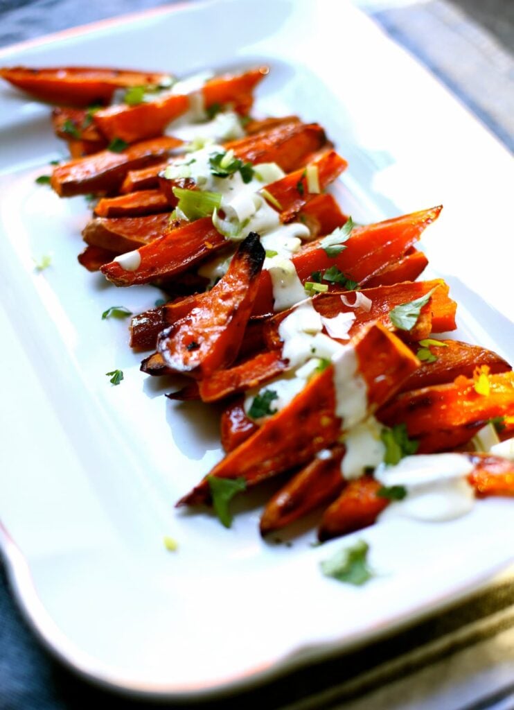 a white platter of roasted sweet potatoes.