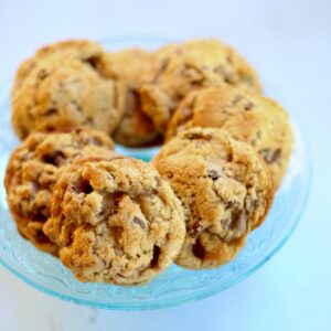 a blue glass dish with chocolate chip cookies on top.