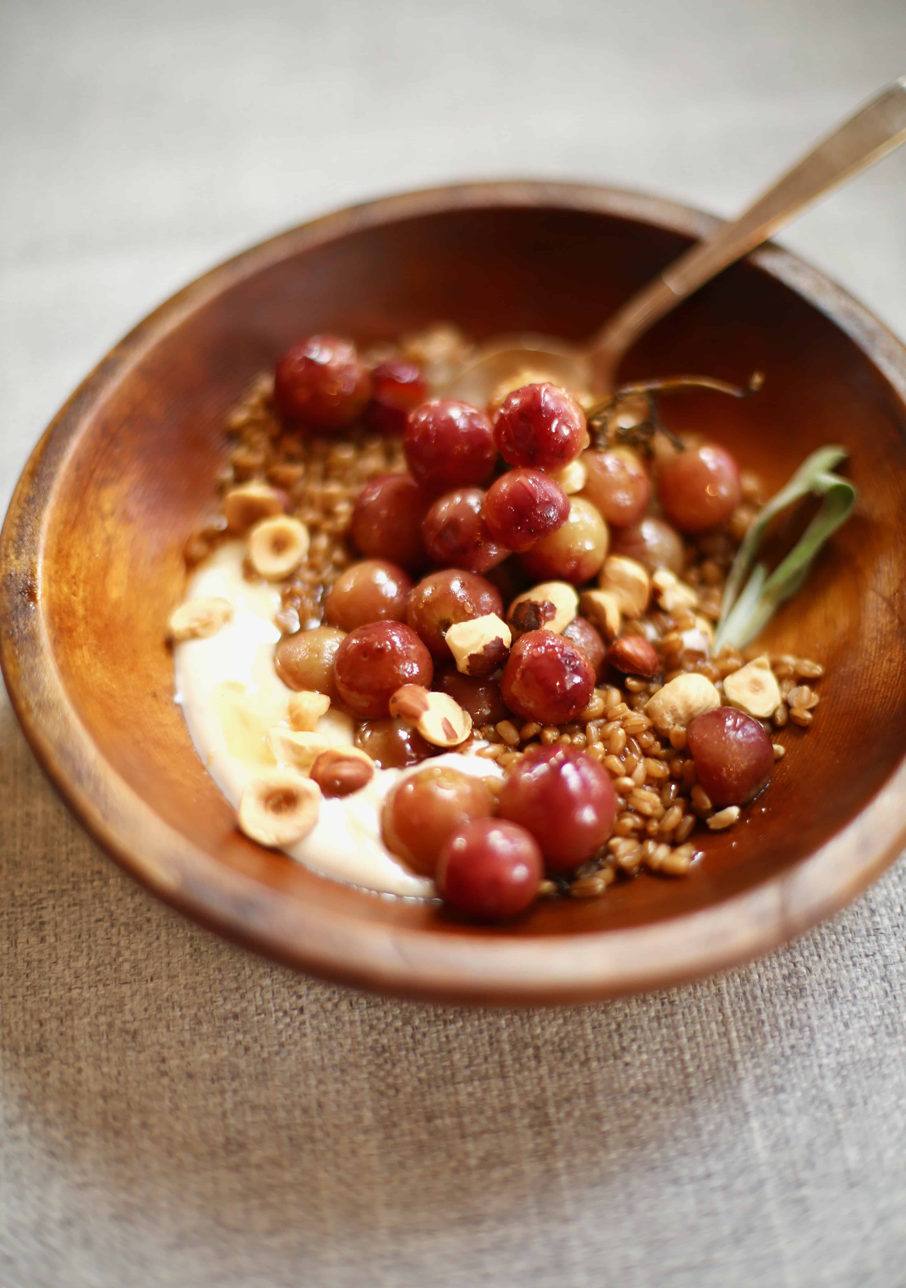 a wooden bowl filled with yogut and grapes