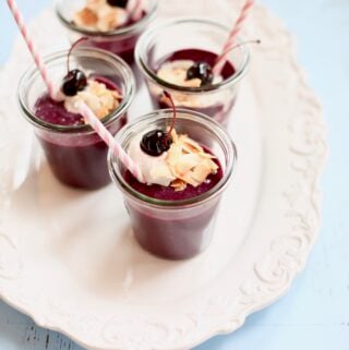 four smoothies on a white platter on a blue table