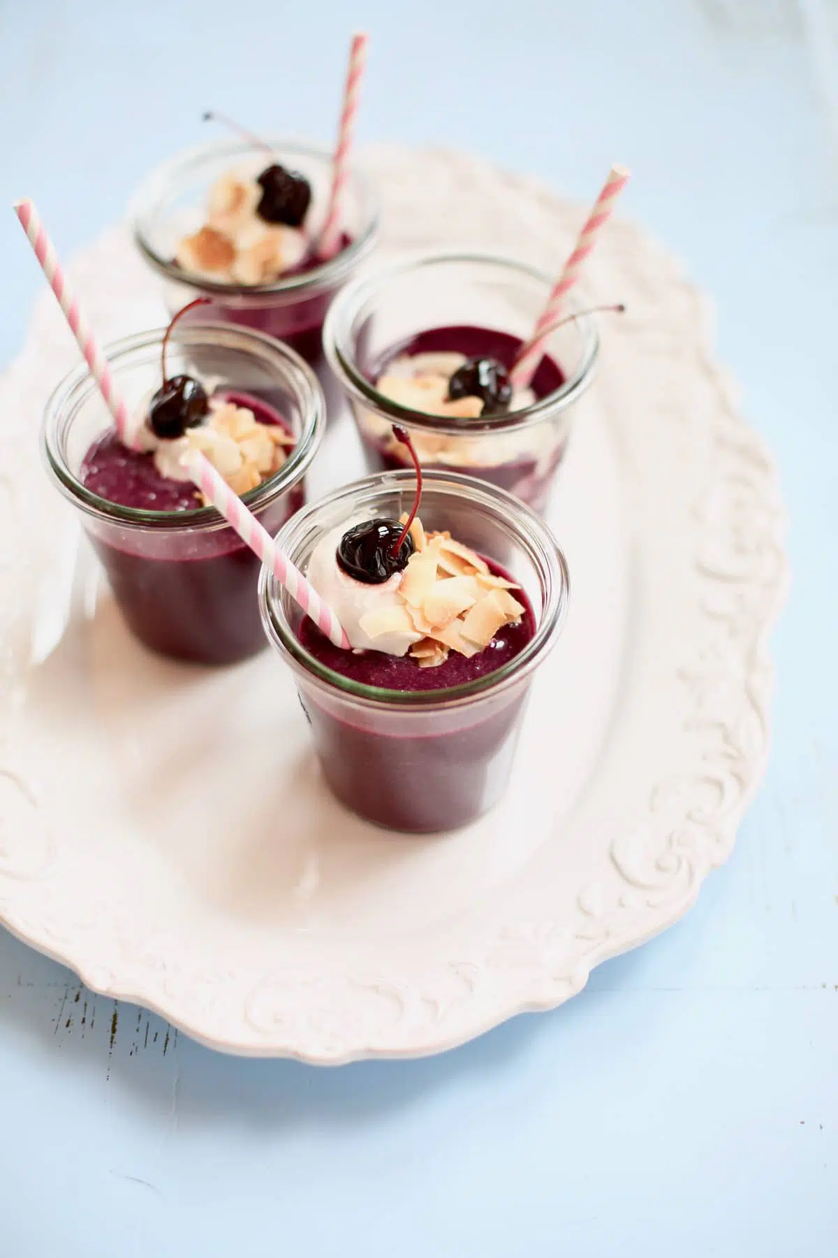 four smoothies on a white platter on a blue table