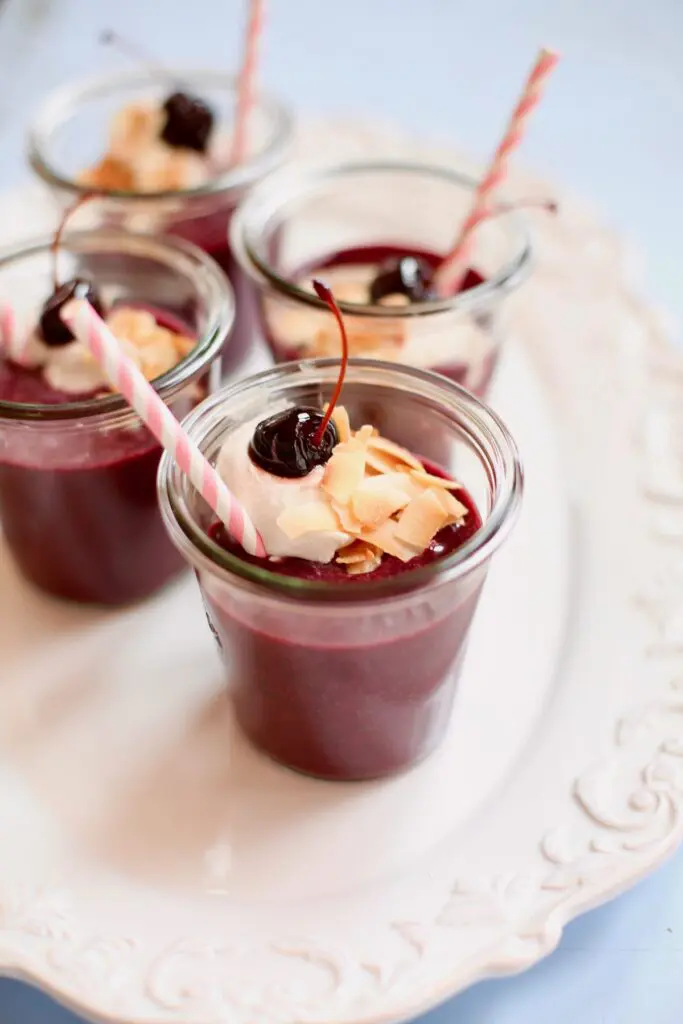 dark cherry smoothies on a tray with pink straws