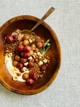 a bowl of grains and grapes in a wooden bowl