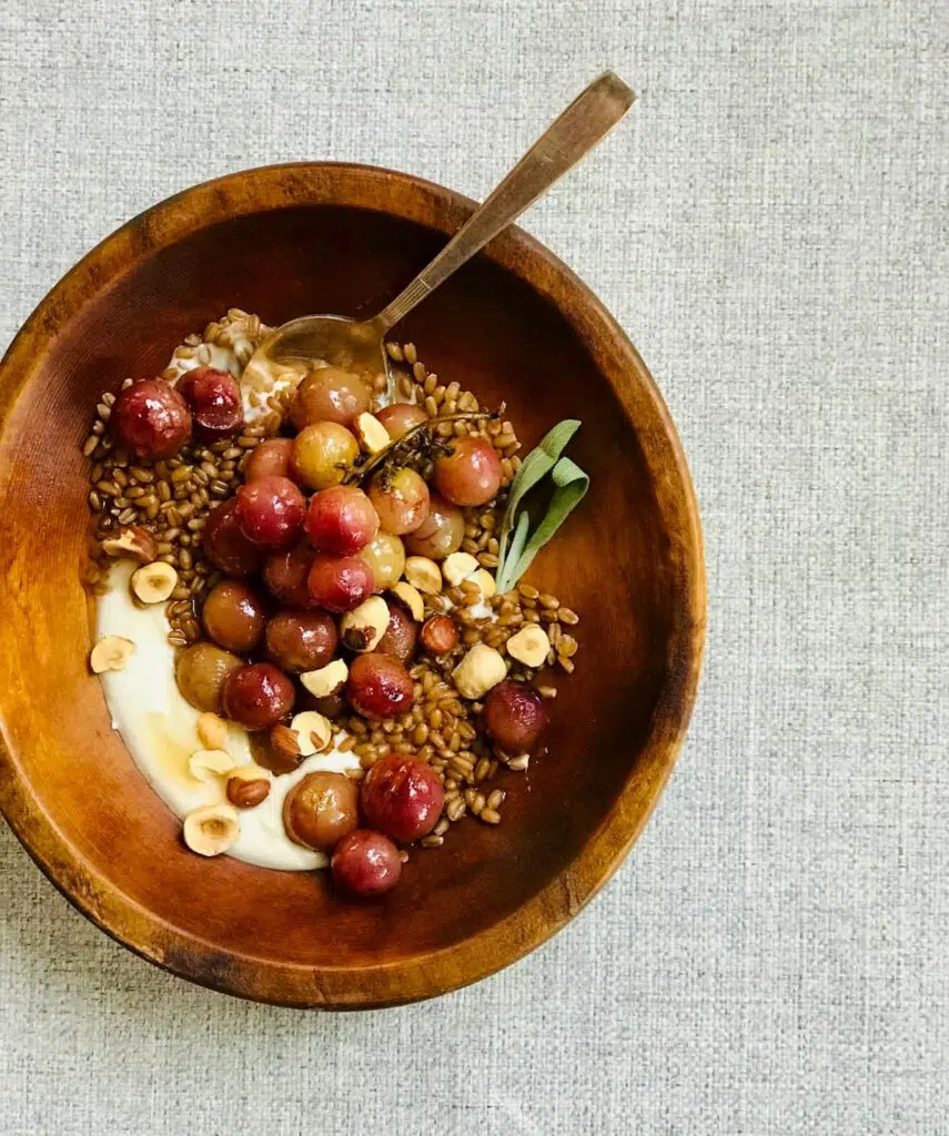 a bowl of grains and grapes in a wooden bowl